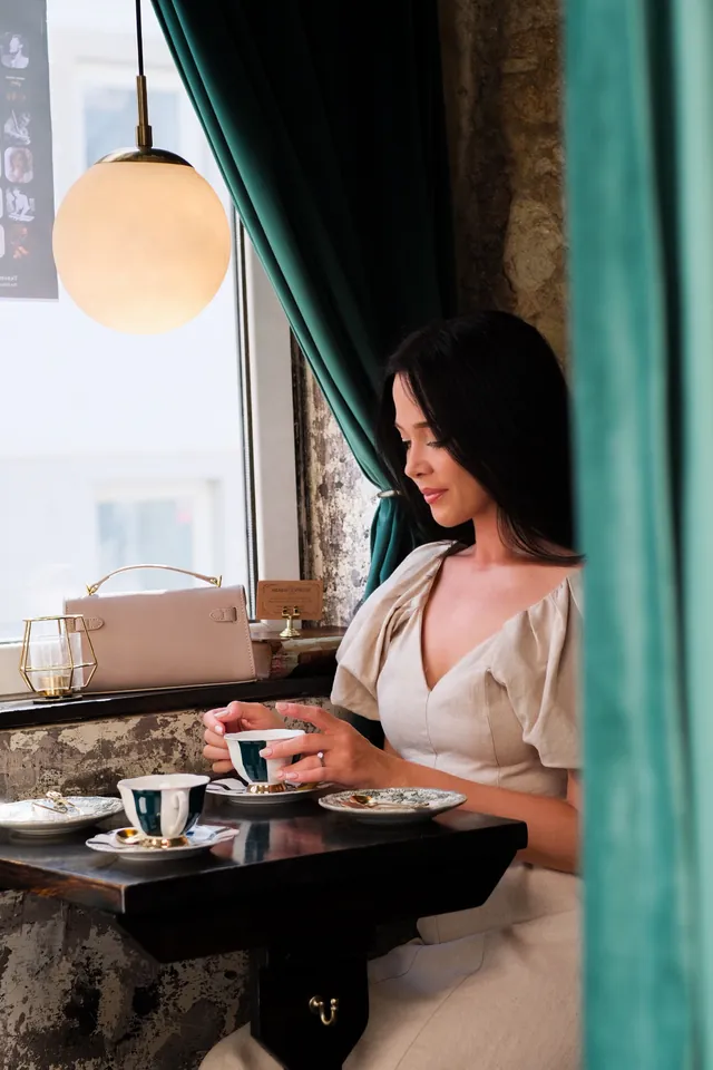 Karolina having coffee at a cafe window in soft morning light