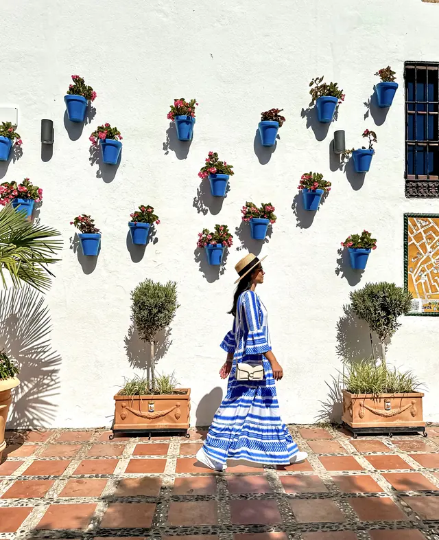 A white wall lined with blue flower pots