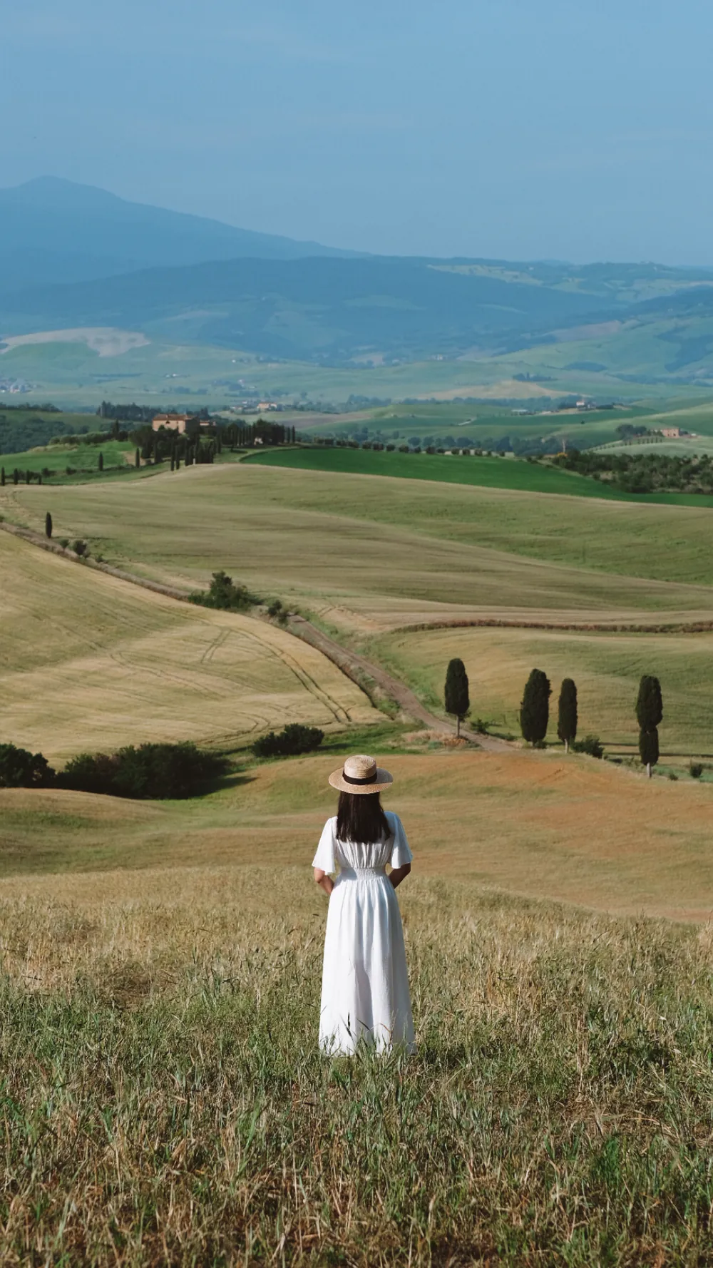 Karolina in a white dress walking through a golden Tuscan field